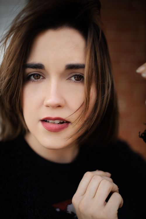 Free Close-up portrait of a young woman with tousled hair expressing confidence and allure. Stock Photo