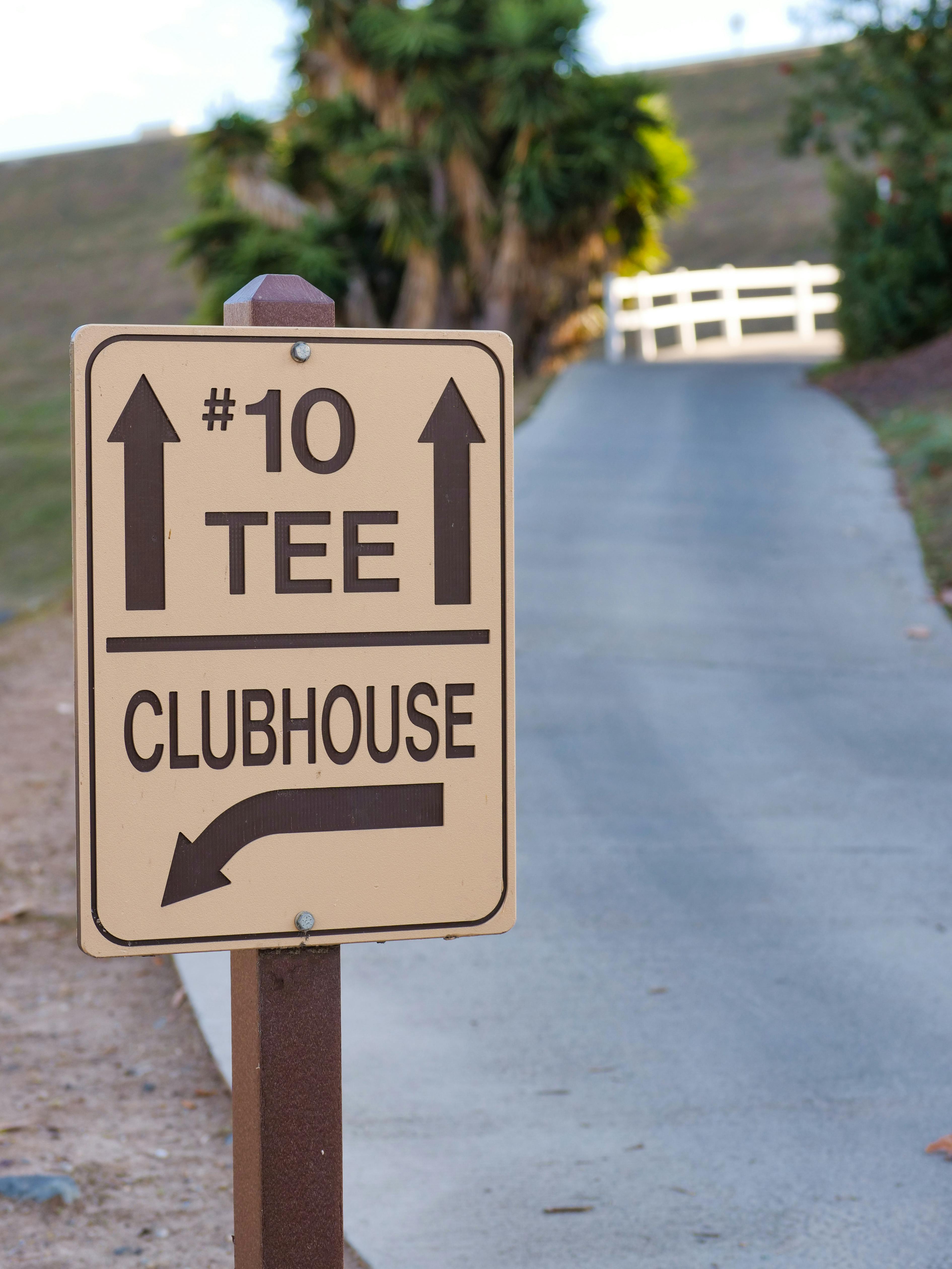Vertical shot of a golf course sign showing directions to #10 tee and clubhouse.