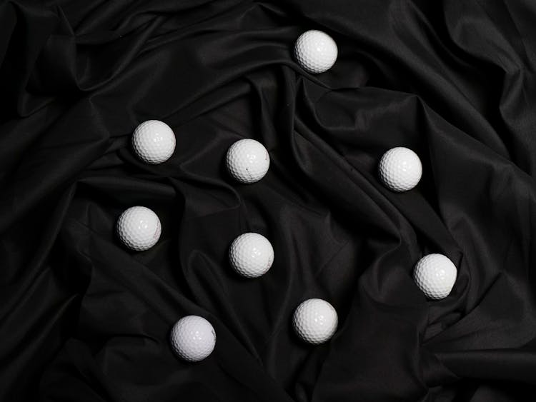 Golf Balls On Top Of A Black Cloth