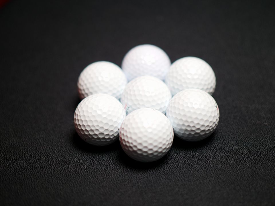 Cluster of plain white golf balls on a dark surface