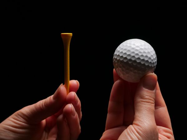 Hand holding a golf ball and wooden tee