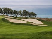 海边的高尔夫球场，多云的天空下有绿色的球道和沙质掩体