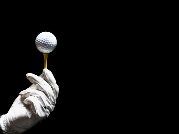 A Person Holding A Golf Tee With Golf Ball