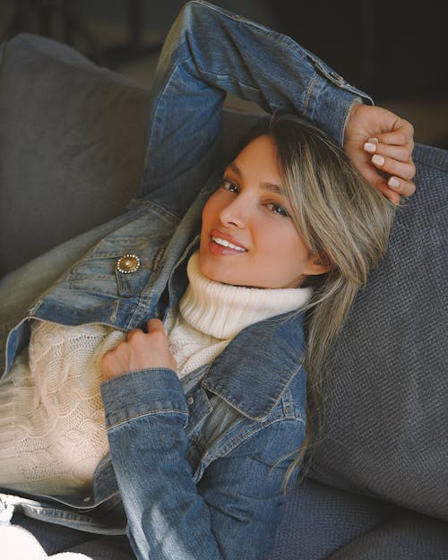 Woman in Denim Jacket Reclining on Gray Sofa