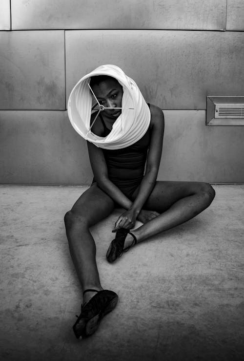 Thoughtful black female dancer relaxing on floor after rehearsal in studio