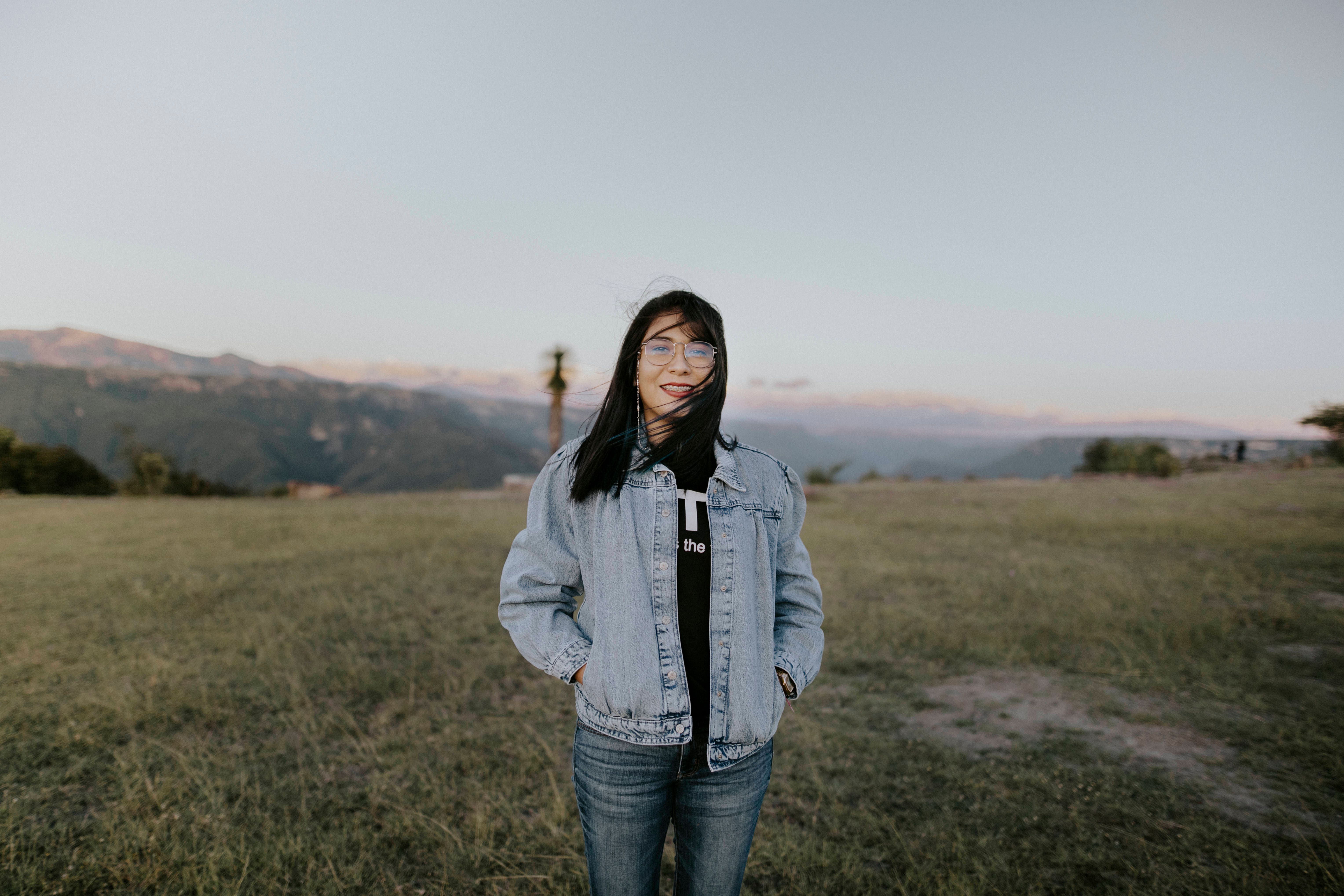 Woman in Denim Jacket Standing on Grass Field · Free Stock Photo