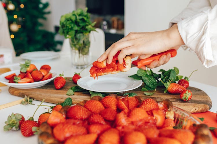 A Person Holding A Sliced Strawberry Pie