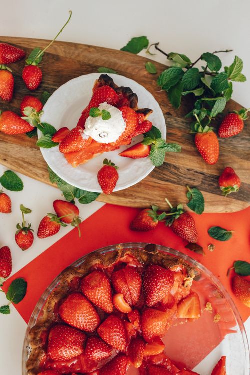 Free Top view of delicious fresh strawberry pie with whipped cream, garnished with mint leaves on a ceramic plate. Stock Photo