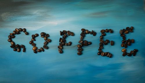 Free Coffee beans form the word 'Coffee' on a gradient blue background, artistic setup. Stock Photo