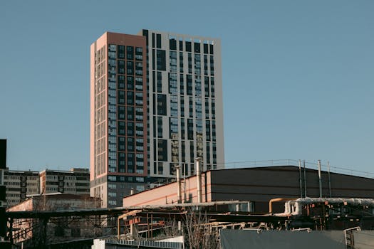 Low angle exterior of contemporary high rise residential building in urban district against cloudless blue sky