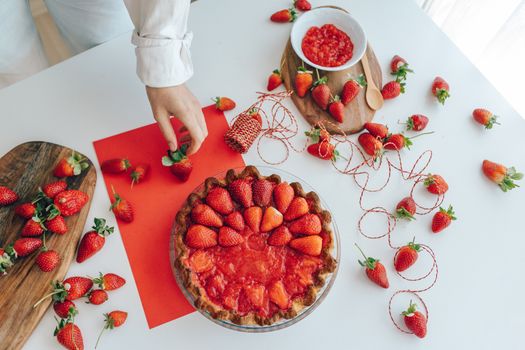 Delicious homemade strawberry pie with fresh strawberries on a white table.