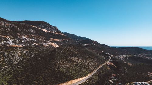 Free Stunning aerial landscape view featuring a mountain road and clear blue sky. Stock Photo