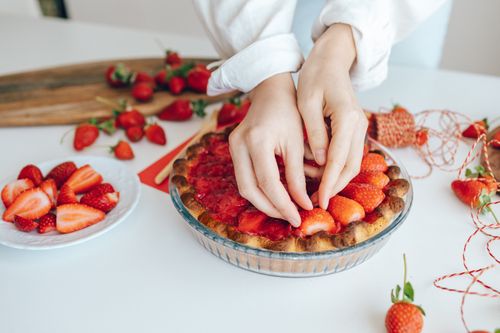 Free Hands arranging fresh strawberries on a pie, showcasing delicious homemade food preparation. Stock Photo