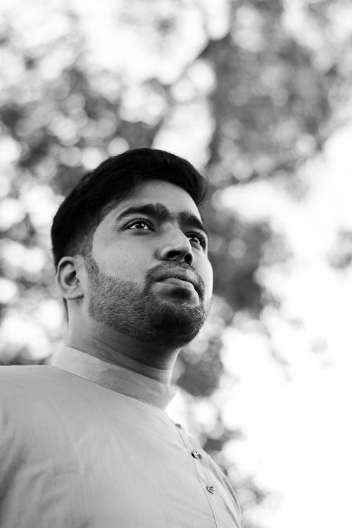 Free Artistic low-angle black and white portrait of a thoughtful South Asian man outdoors. Stock Photo