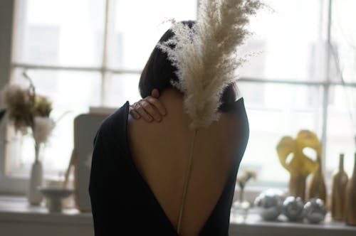 Back view of anonymous female with pampas grass on back touching gentle neck on blurred background of interior of kitchen