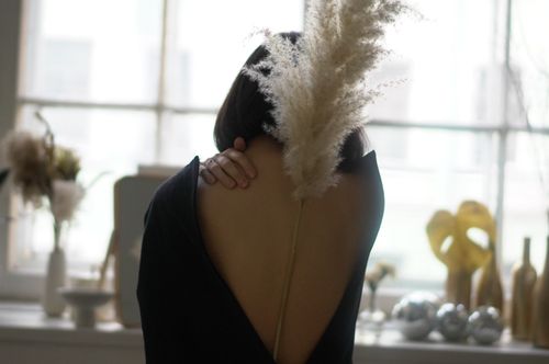 Free Back view of anonymous female with pampas grass on back touching gentle neck on blurred background of interior of kitchen Stock Photo