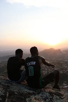 Two men admire the sunset over Yaounde's landscape. Introspective and serene moment.