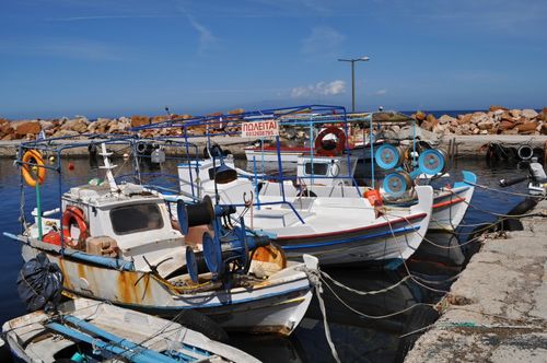 Free Colorful fishing boats docked at a harbor in Chios, Greece with clear blue water and sky. Stock Photo