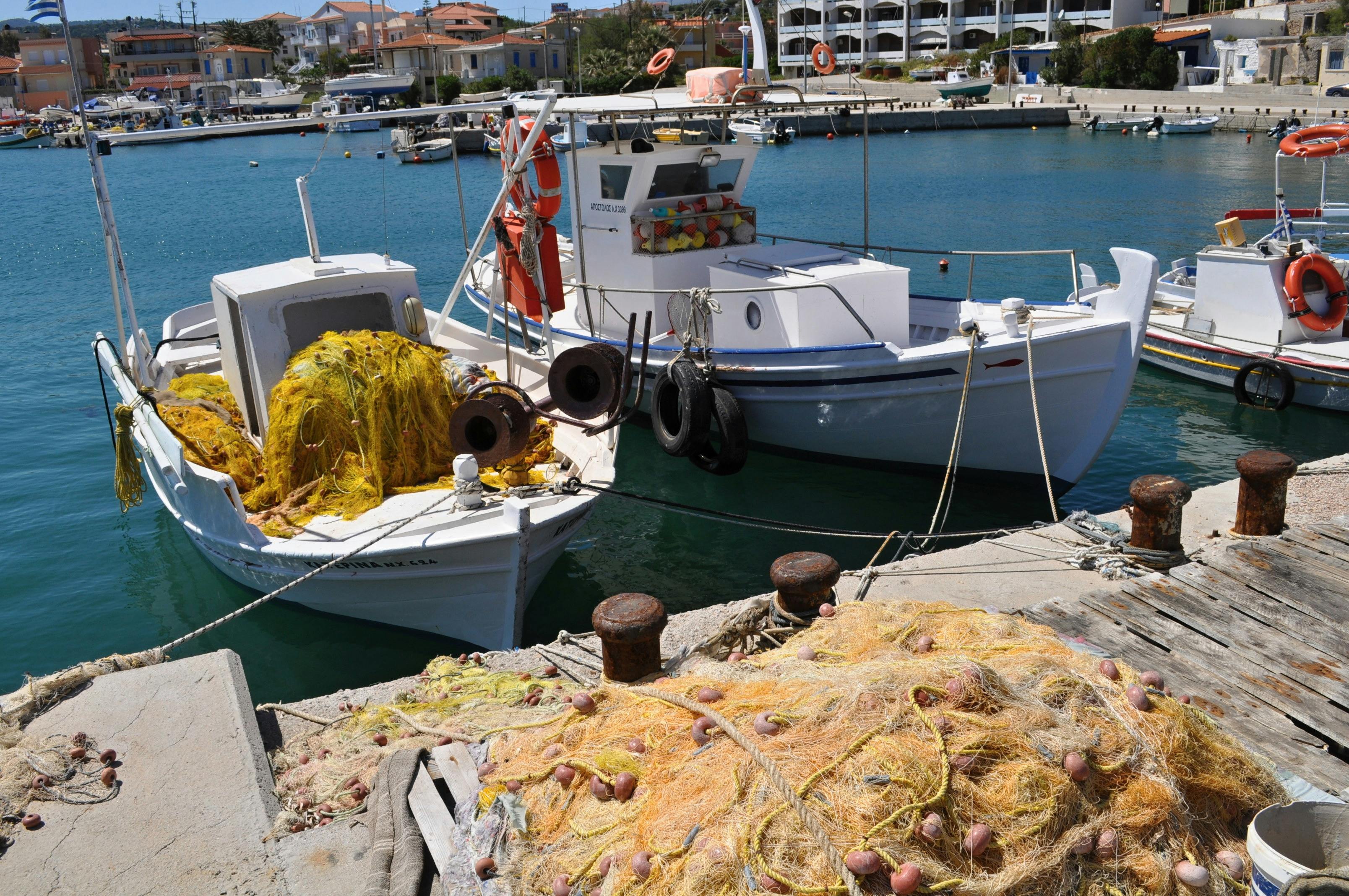 Free Colorful fishing boats with nets docked at a serene seaside pier. Stock Photo