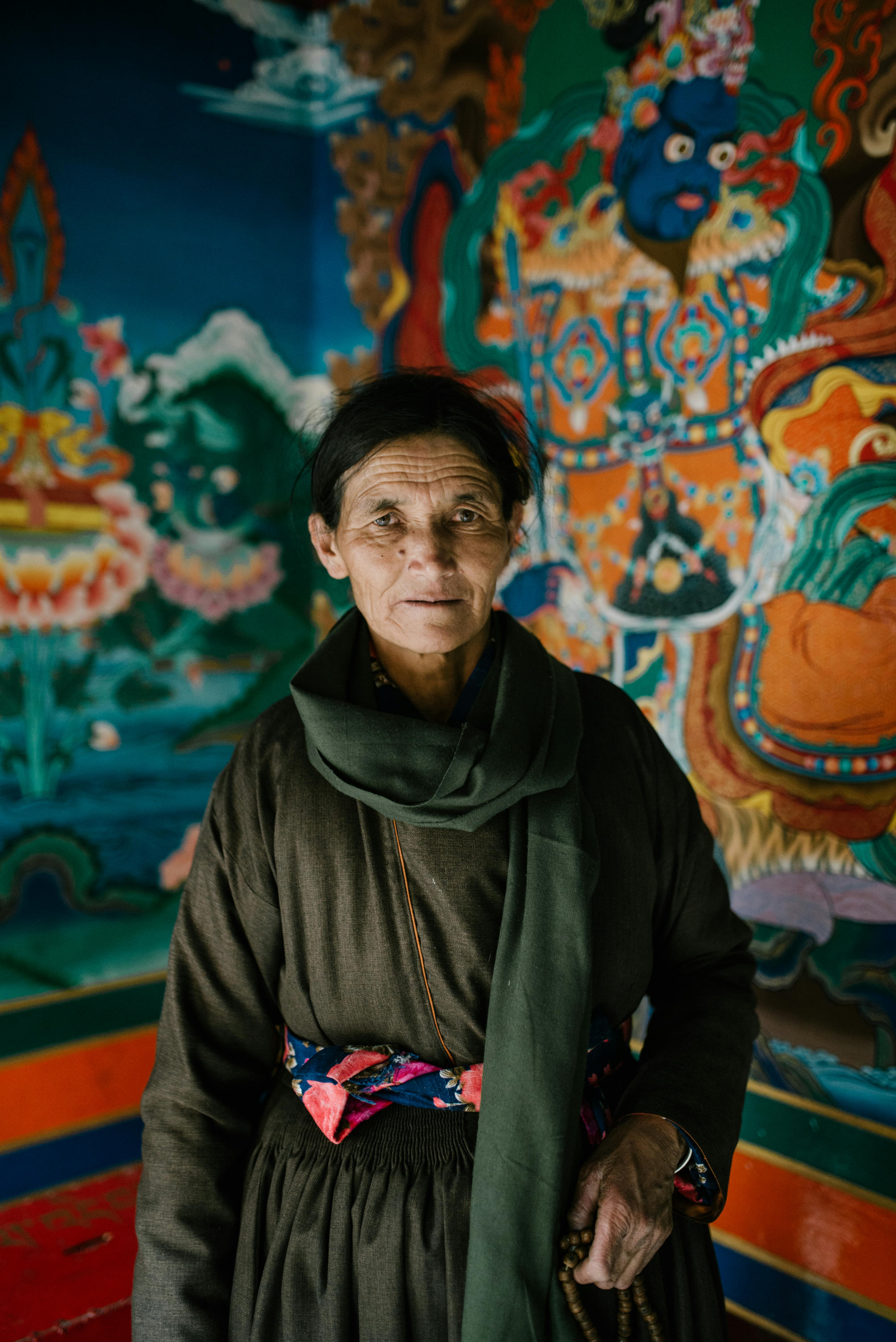 Portrait of a senior woman in traditional attire with a vibrant mural background.