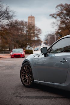 A sleek car parked on an urban street with a distant cityscape, highlighting modern automotive design.