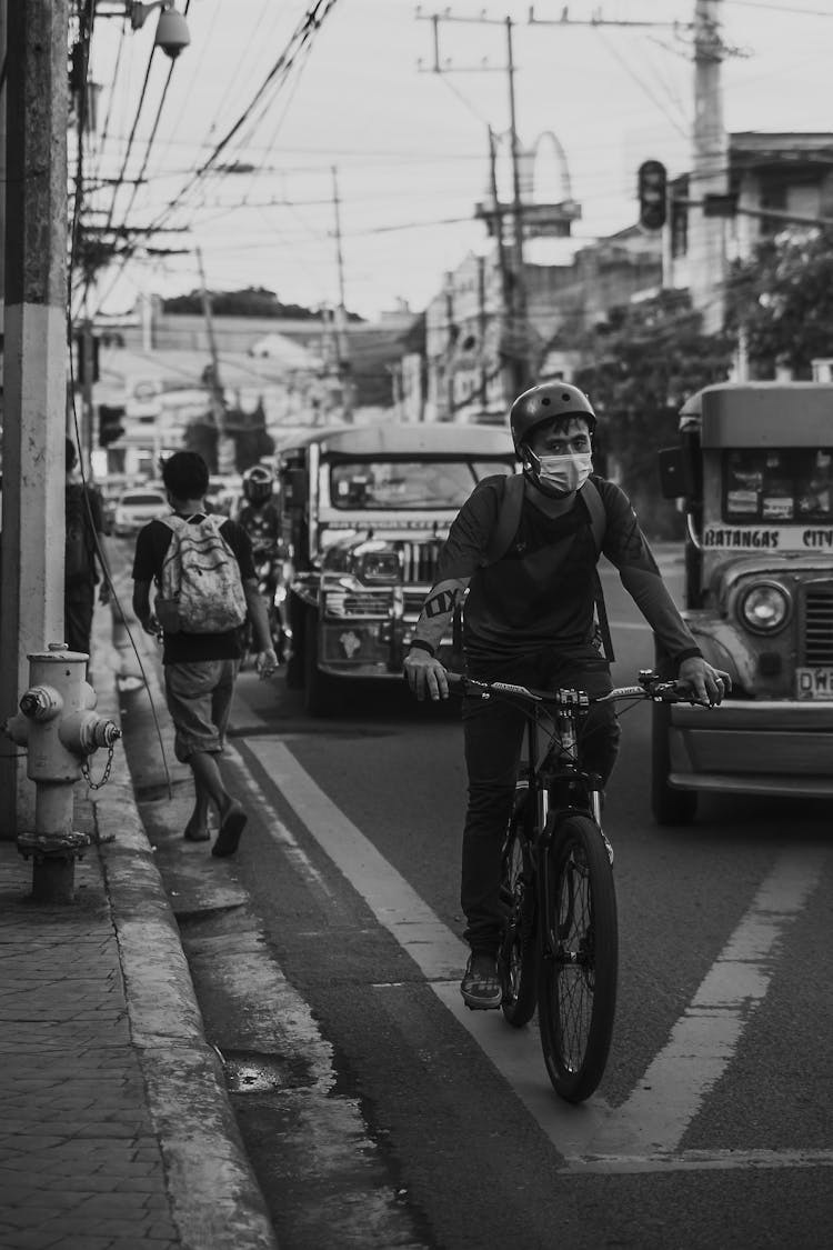 Bicyclist In Protective Mask Riding Bike On Asphalt Road