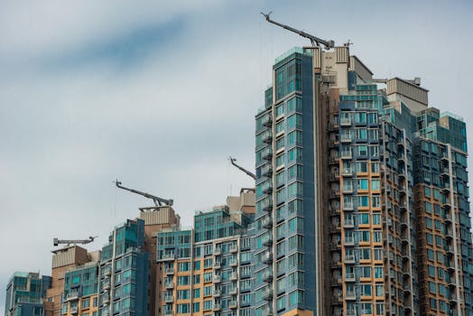 Stunning modern high-rise buildings with cranes in Hong Kong city under a cloudy sky.