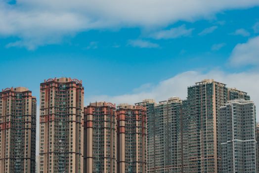Panoramic view of Hong Kong skyscrapers against a vibrant blue sky with clouds.