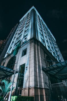 低角度视角下的现代摩天大楼，在夜间照明中展现城市建筑风貌