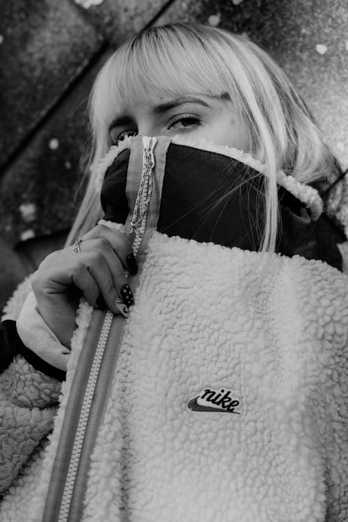 Grayscale Photo of Woman Covering Her Face with Jacket 