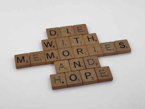Wooden Scrabble tiles arranged to form the motivational quote 'Die with memories and hope'.