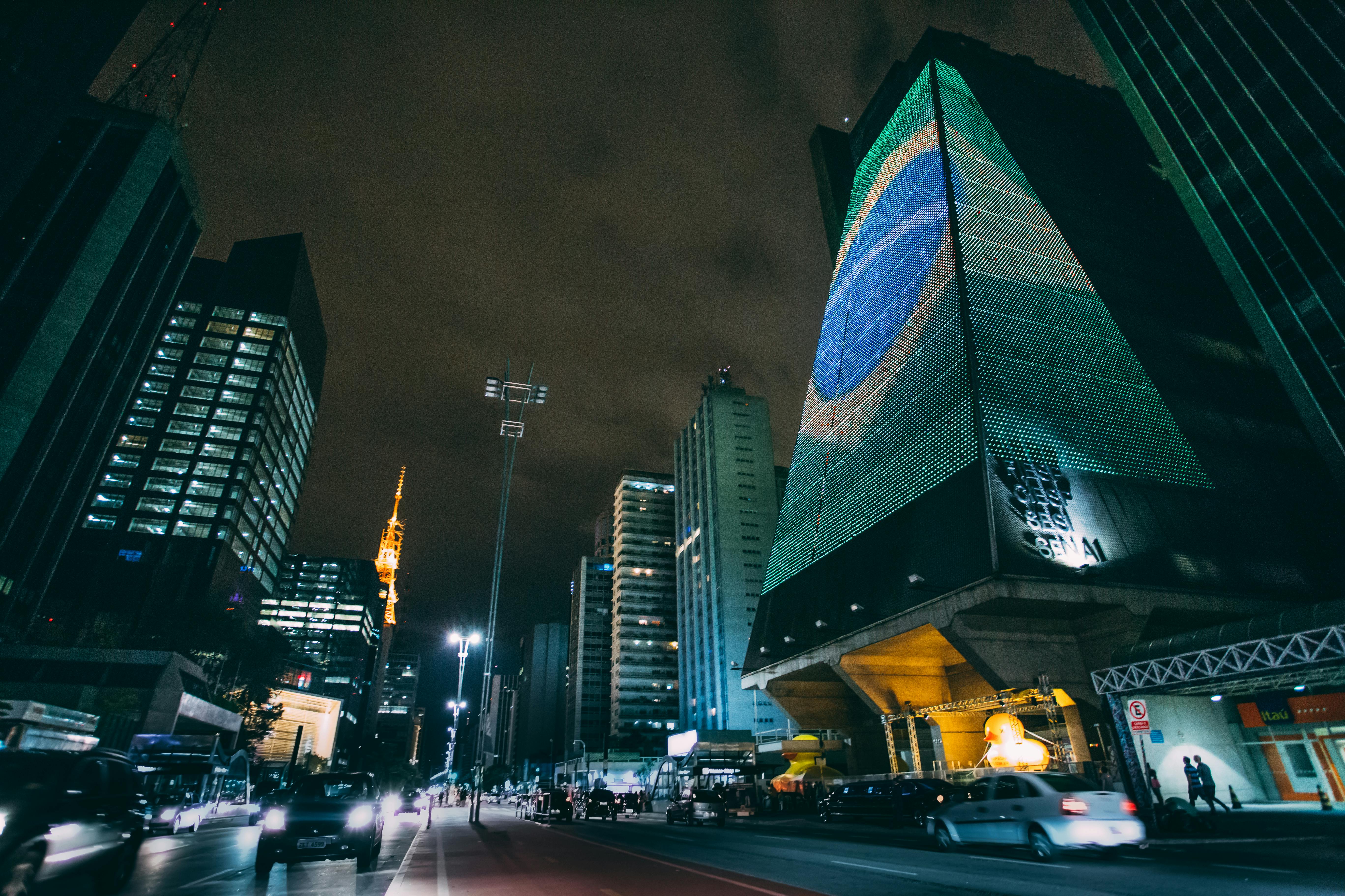 cars traveling on road between buildings during nighttime