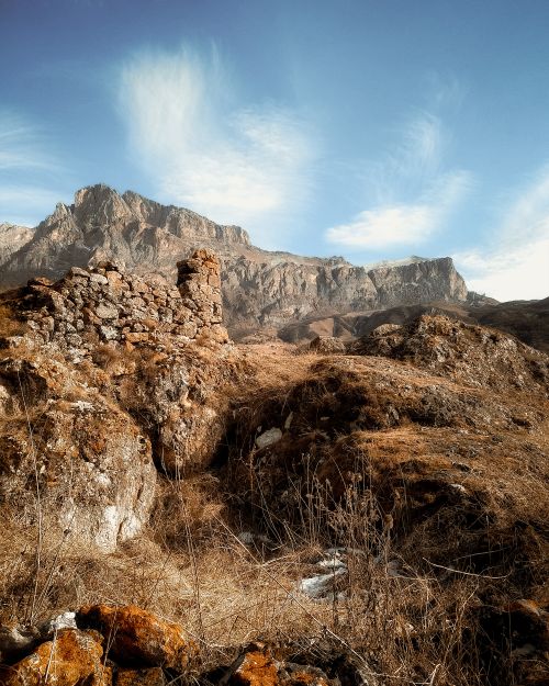 Free Scenic view of rocky mountain landscape with ancient ruins under a vibrant blue sky offering a picturesque nature scene. Stock Photo