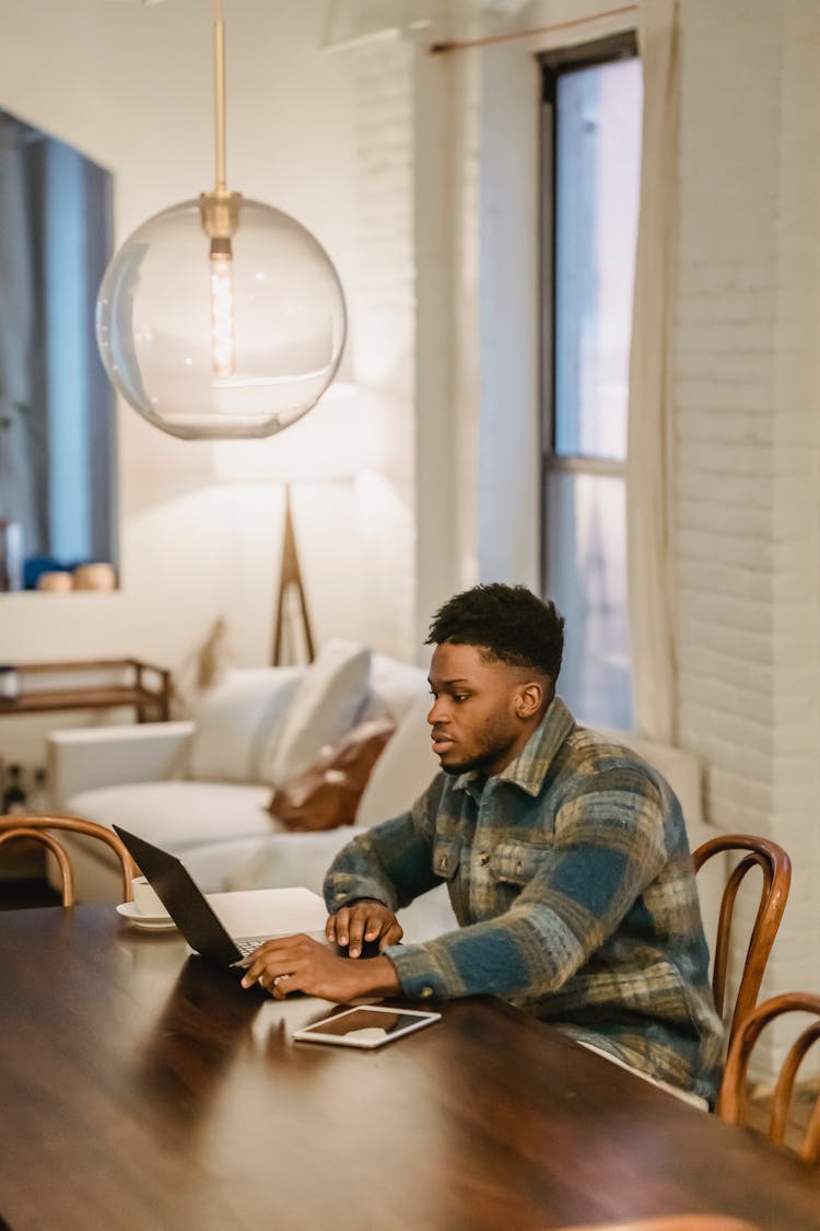 Serious Black Man Working On Laptop At Home