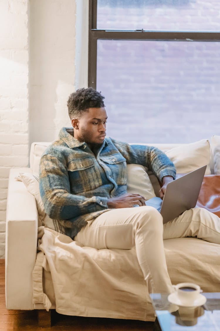 Focused Young Man With Laptop On Sofa