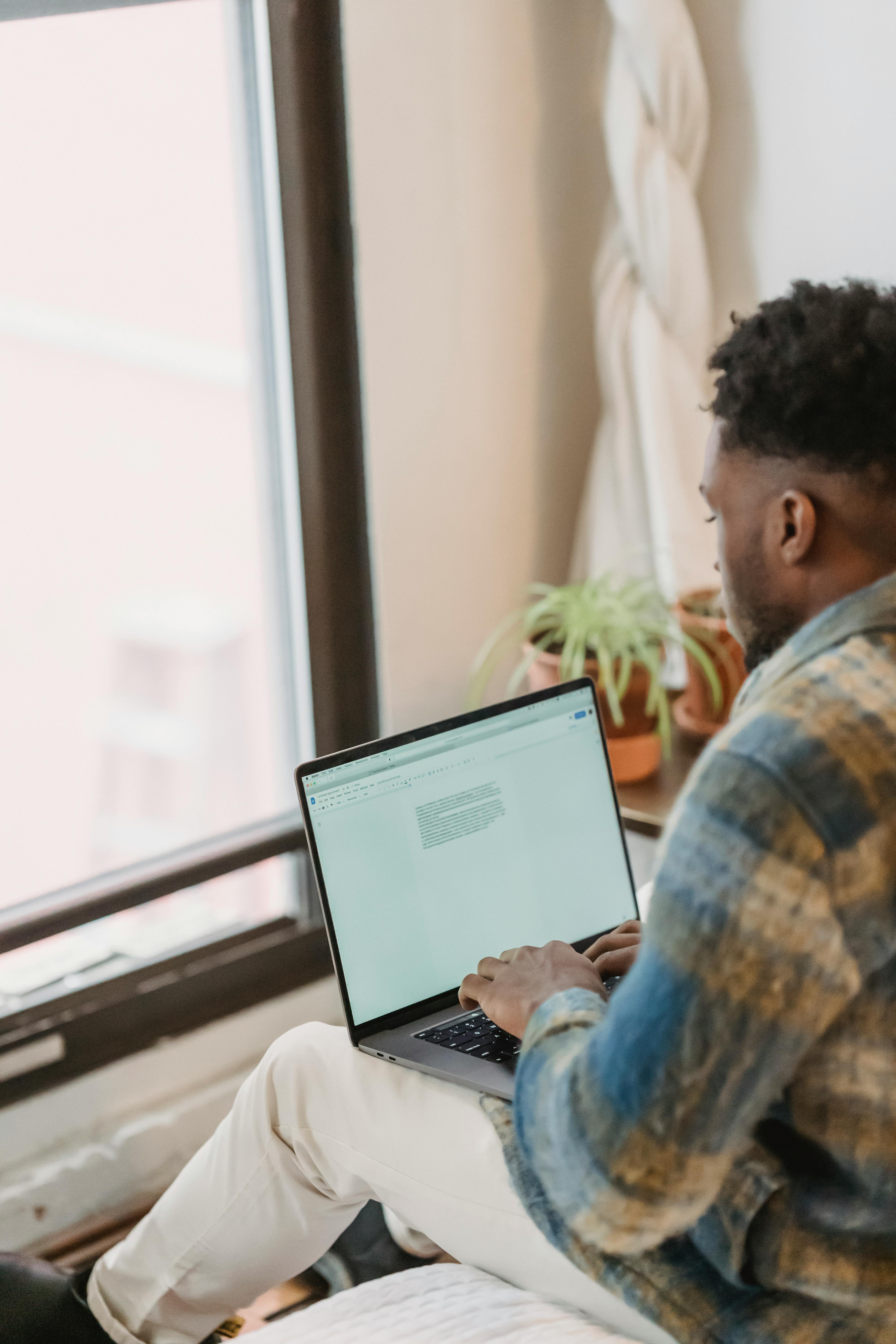 young black guy using laptop in front of window
