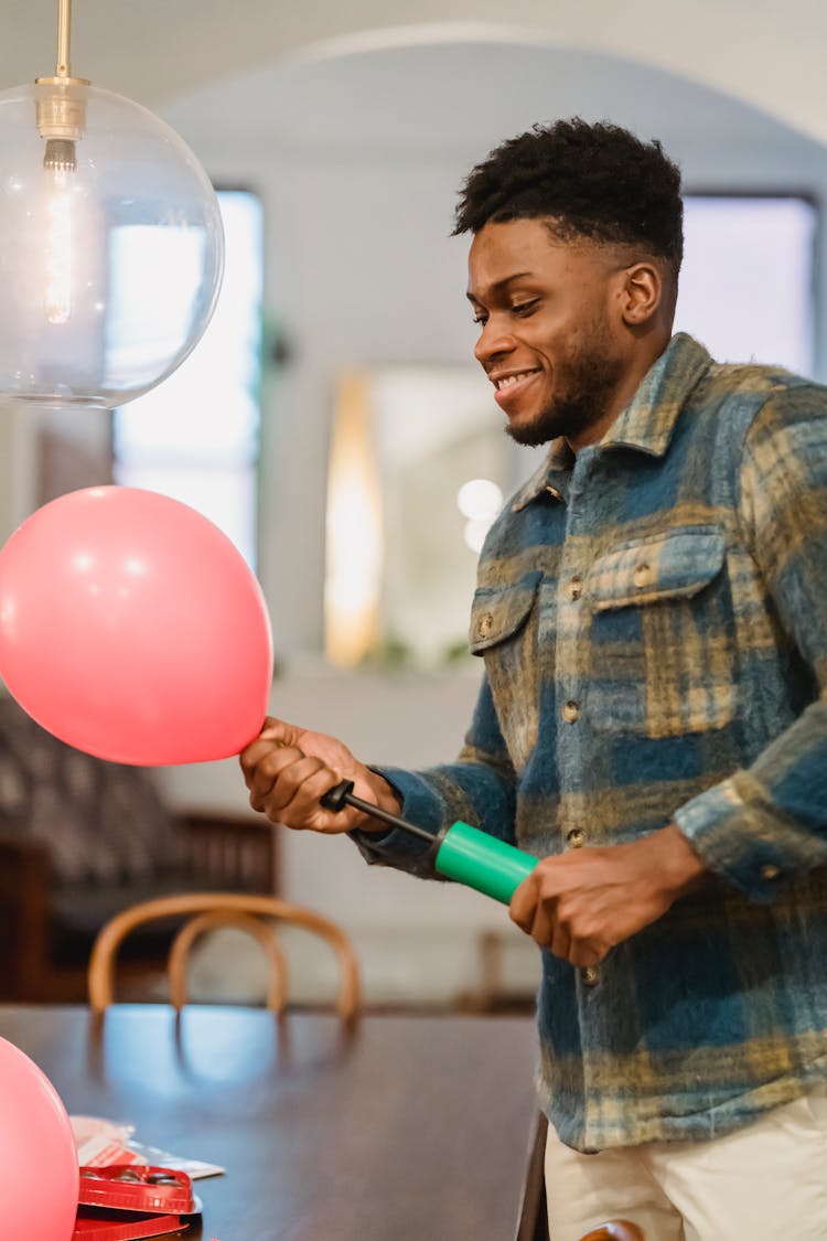 Cheerful Black Man Inflate Balloons With Pump