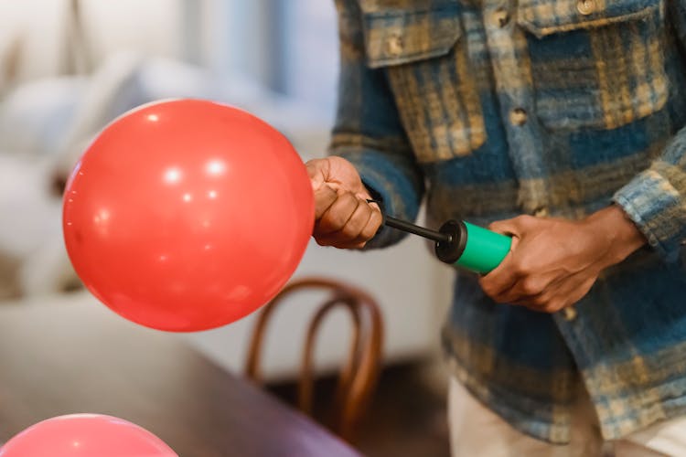 Faceless Ethnic Guy Using Manual Air Inflator While Blowing Balloons At Home