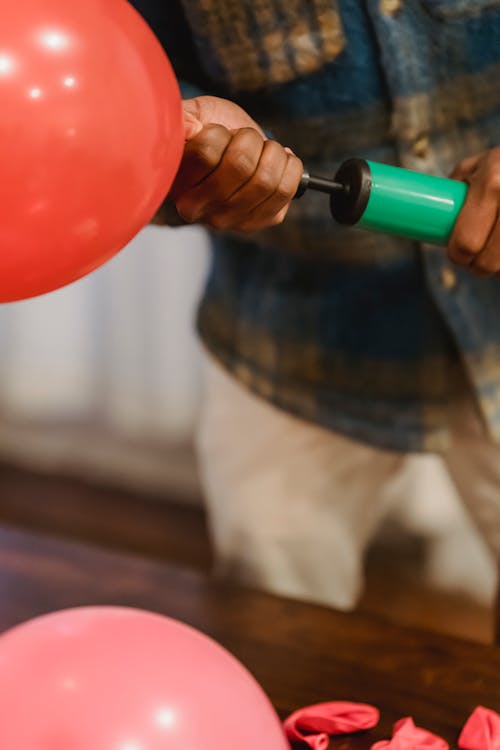 Black man inflating balloon with pump