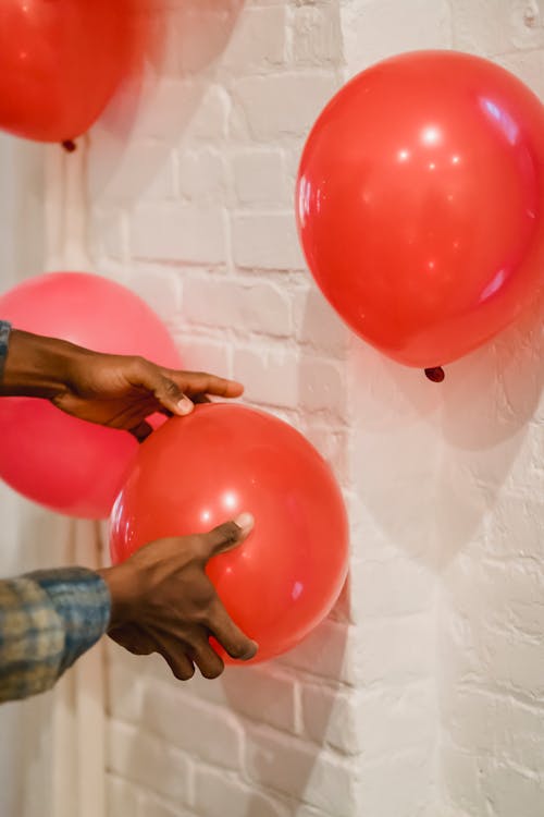 Black man putting red balloons on wall