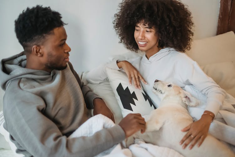 Positive Black Couple Stroking Dog On Bed