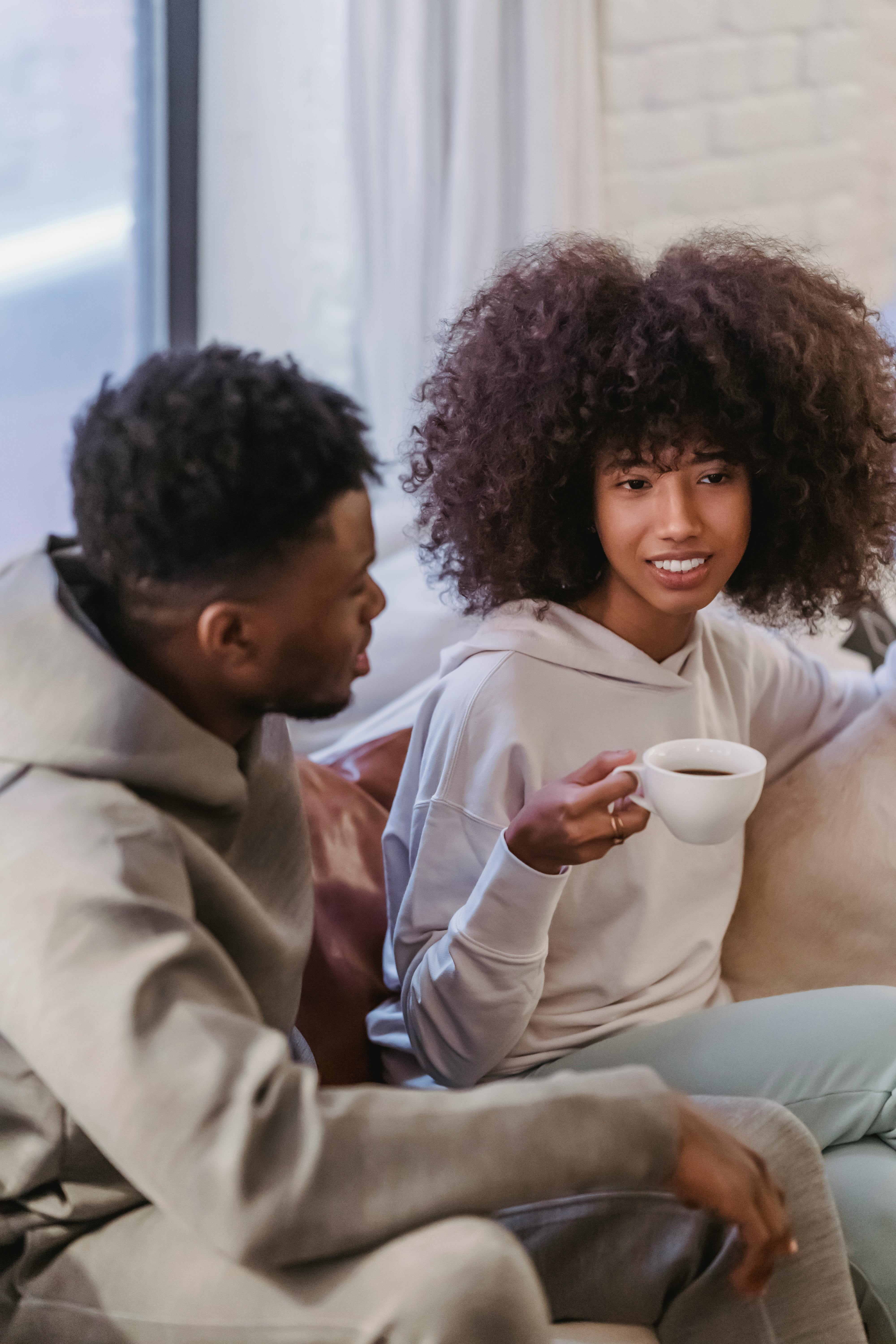 black girlfriend with cup of coffee listening boyfriend