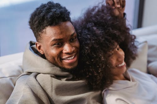 Free Loving positive black couple smiling and resting on sofa Stock Photo