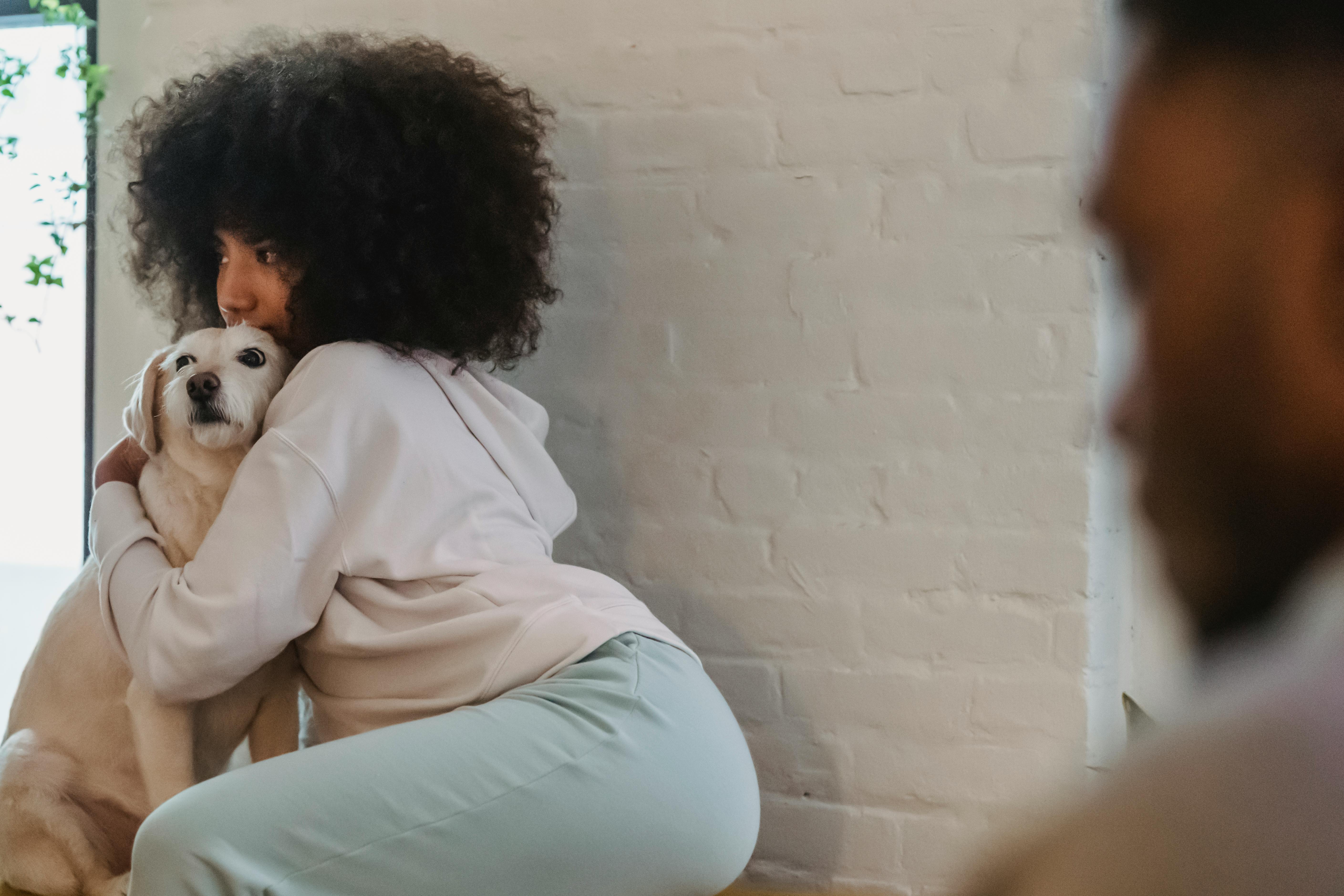 black woman hugging dog in light room