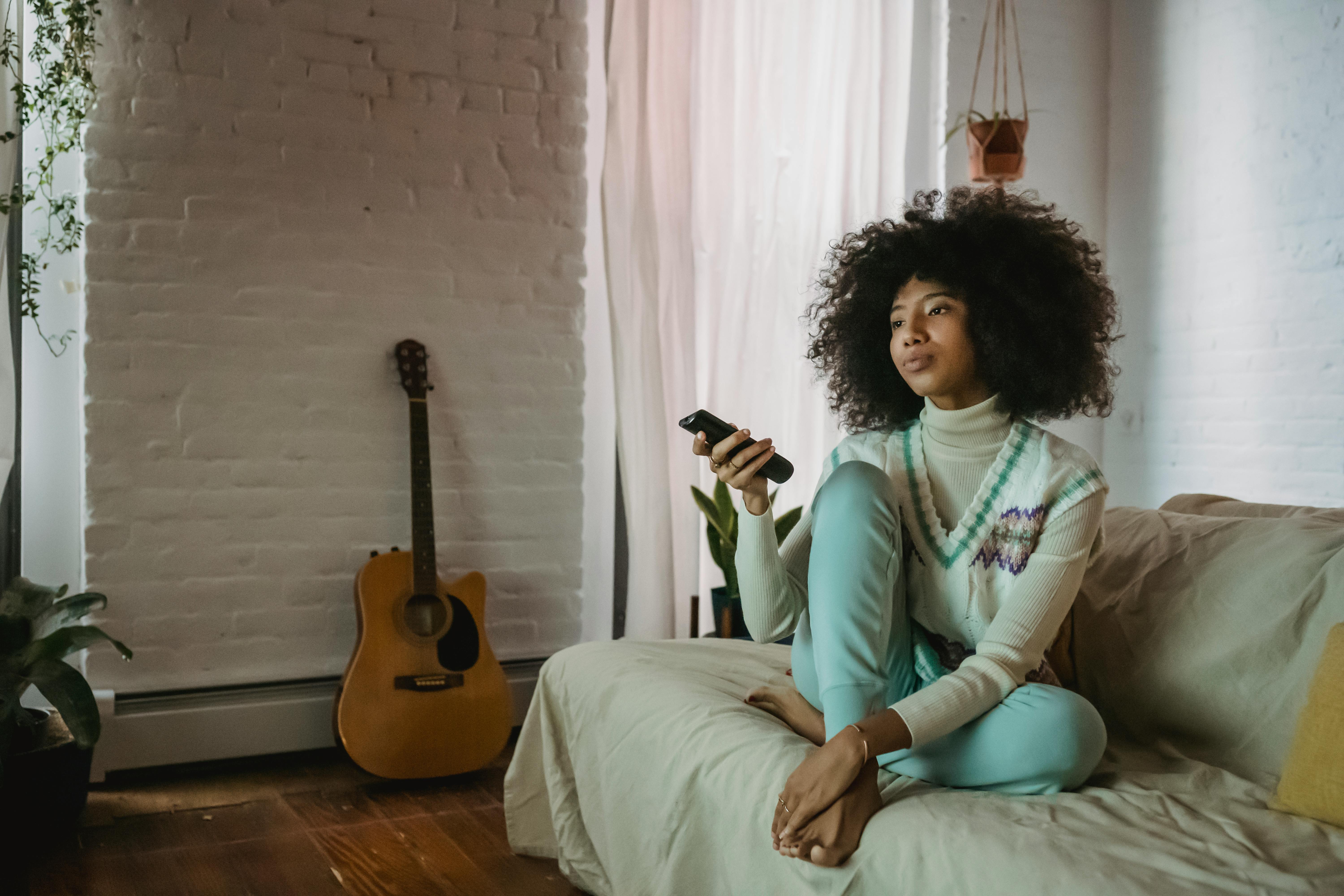 young black lady resting on sofa and watching tv at home