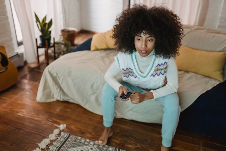 Focused Young Black Lady Watching TV On Couch