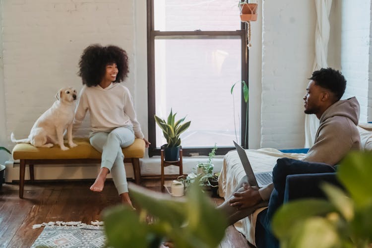 Positive Young Black Couple Chatting While Spending Weekend Together At Home With Cute Dog