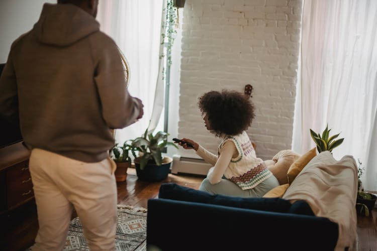 Unrecognizable Black Man Walking In Living Room While Girlfriend Watching TV