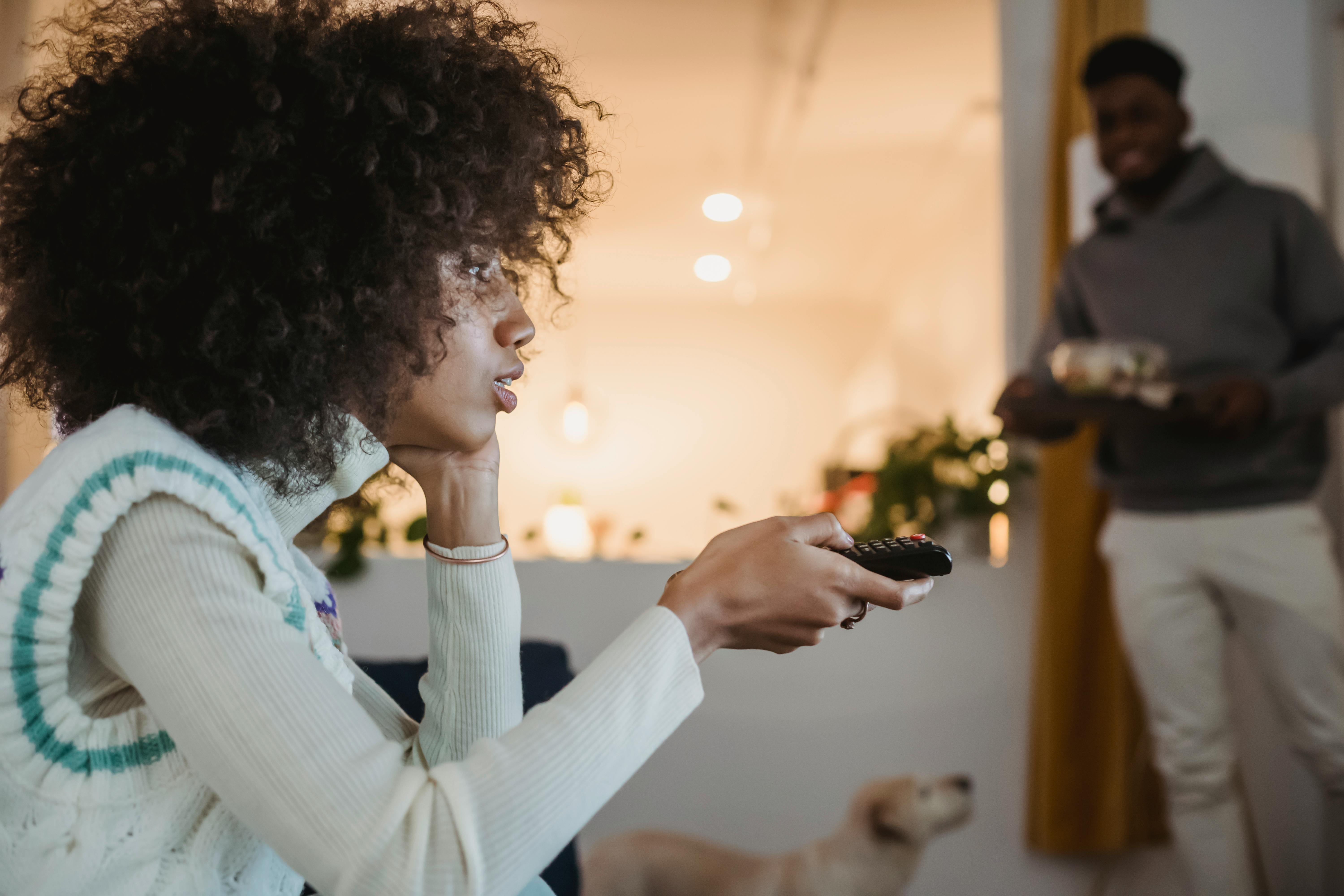 young black woman watching tv with interest near boyfriend standing in room