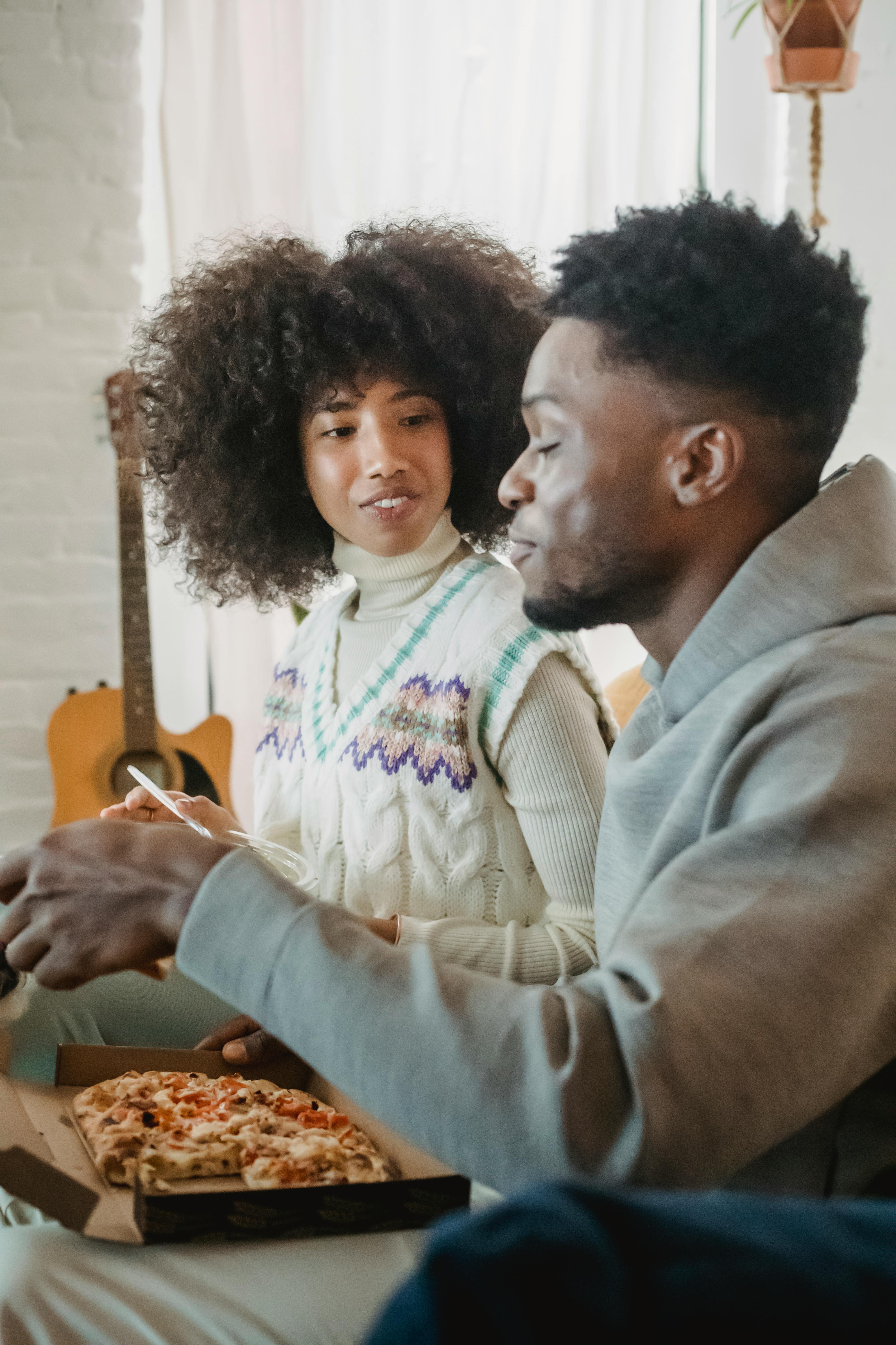 beloved young black couple eating appetizing pizza sitting together on couch